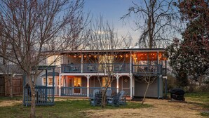 A two-story house with a balcony, a porch, and outdoor seating.
