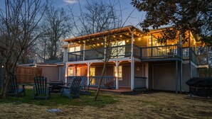 A two-story house with a balcony, outdoor seating, and a covered patio area.