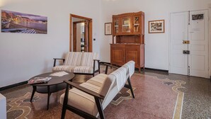 A living room with striped sofas, a coffee table, a wooden cabinet, and a door with a lock. - Lovely apartment for 4 people with WIFI, TV and balcony (Sestri Levante)