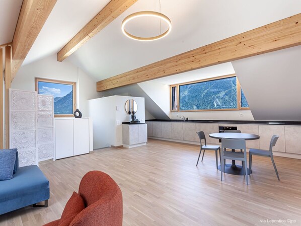 A modern kitchen with a large window, wooden beams, and a dining area with chairs.