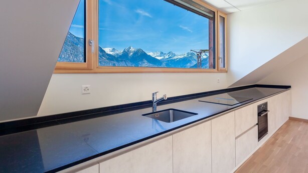 A modern kitchen with a large window overlooking a mountainous landscape.