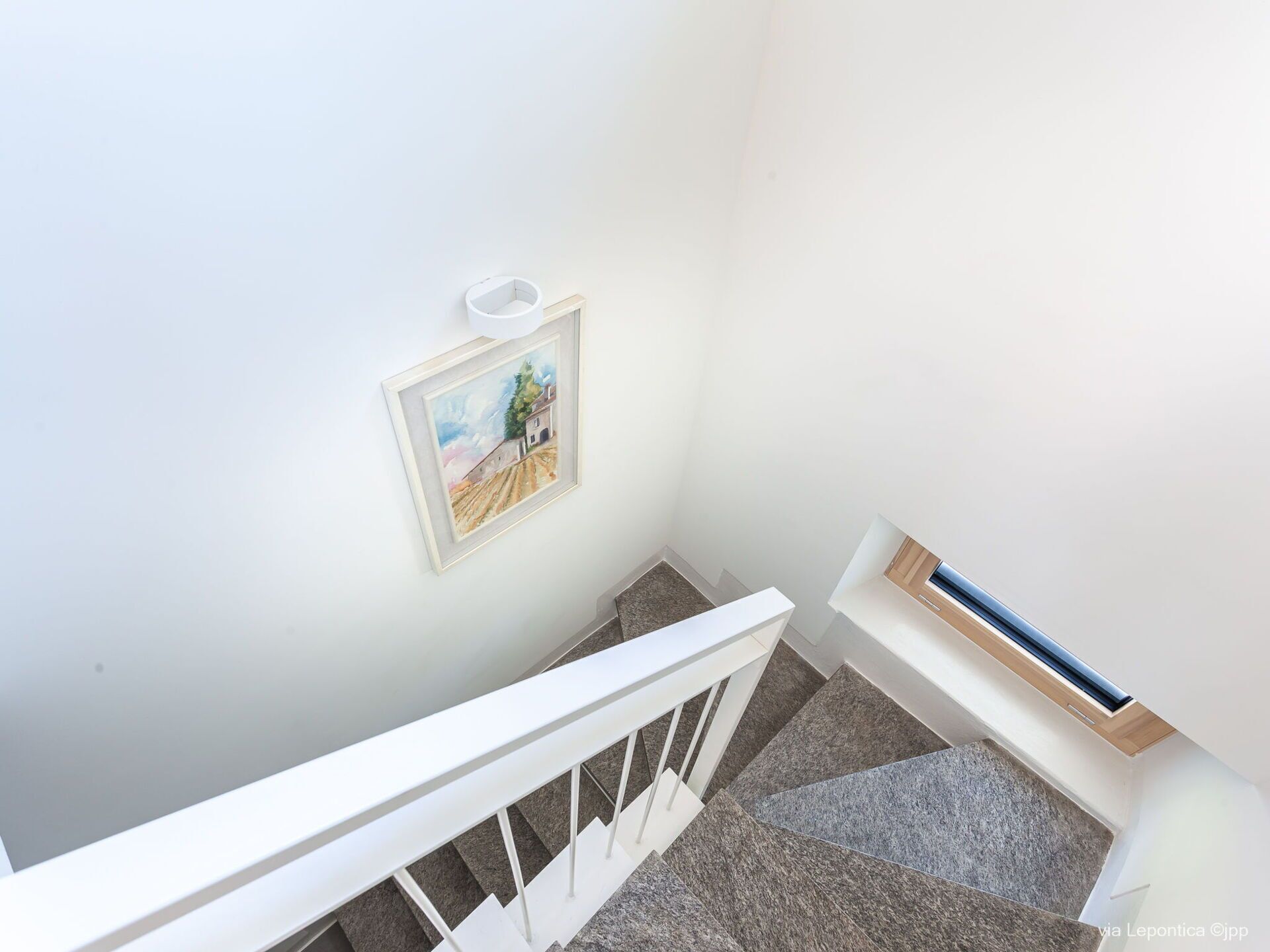 Una escalera con barandilla blanca y un cuadro enmarcado en la pared.