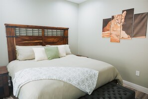 A neatly made bed with a wooden headboard, a bedside table, and a wall-mounted artwork of a lion.
