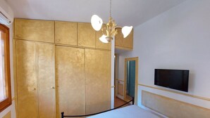 Quarto com cama, televisão na parede e guarda-roupa.