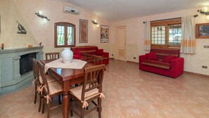 Uma sala de estar ampla com área de jantar, sofás vermelhos, lareira e uma janela grande.