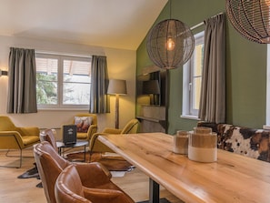 Una sala de estar moderna con una mesa de comedor de madera, sillas de cuero y un sofá con un plaid estampado.
