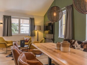Uma sala de estar moderna com uma mesa de jantar de madeira, cadeiras de couro e um sofá com manta estampada.