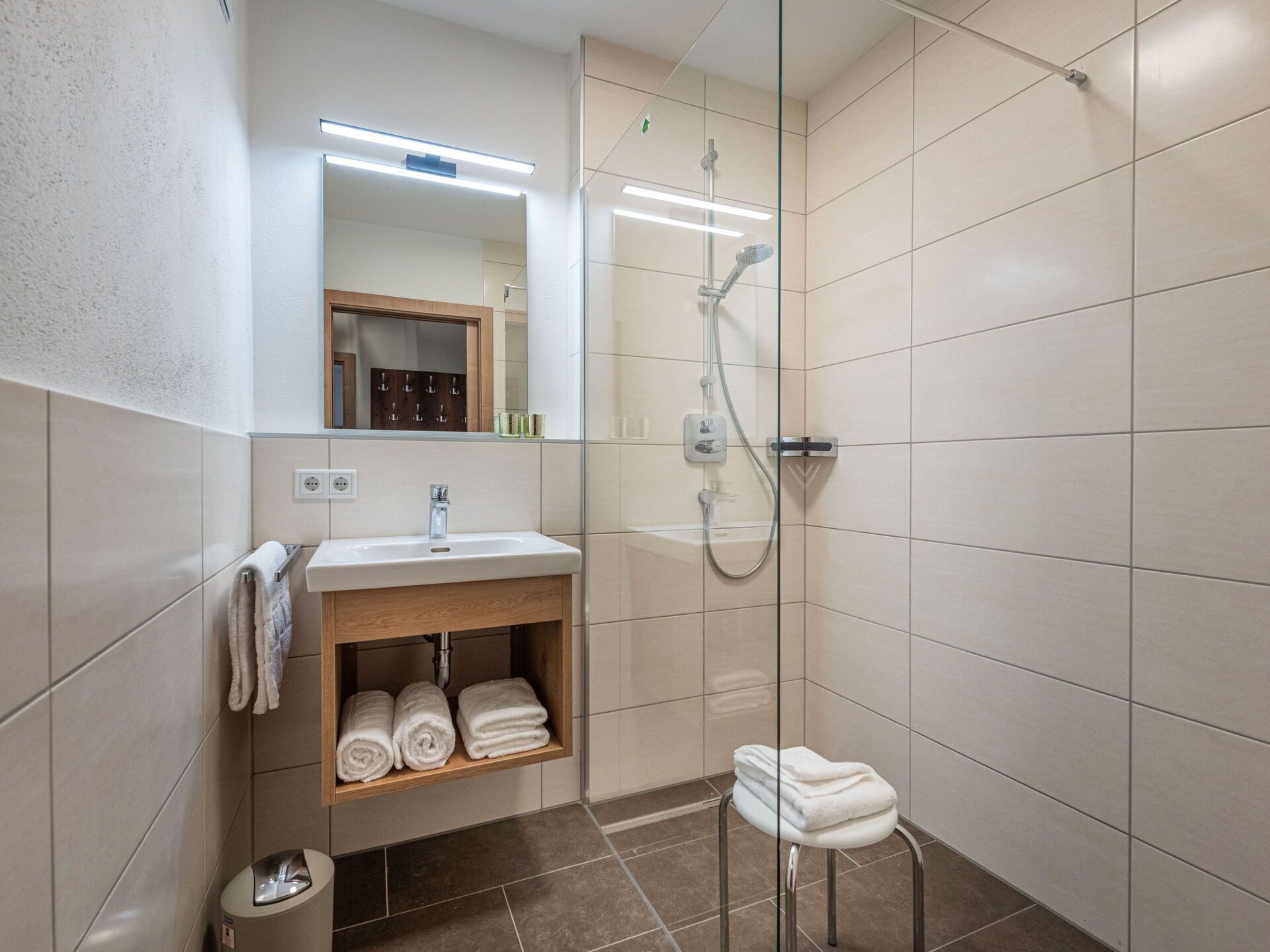 Un bagno moderno con cabina doccia in vetro, lavabo con specchio e portasciugamani.