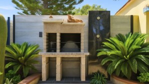 A modern outdoor kitchen with a stone countertop and a built-in oven, surrounded by potted plants and a tiled patio. - Beautiful apartment for 4 people with WIFI, pool, A/C, TV and panoramic view (Villasimius)