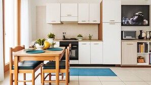 Une cuisine moderne avec des meubles blancs, une table à manger avec des chaises et un tapis bleu.