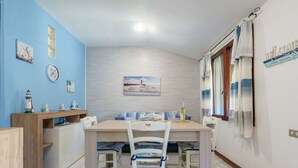 Un comedor con mesa y sillas de madera, un reloj y decoración temática náutica.