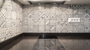 Una cucina con piastrelle decorate, un piano cottura a induzione nero e una lampada a soffitto.
