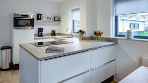 A modern kitchen with a central island, built-in oven, coffee maker, and a window with a view of the outside. - Wonderful private villa for 6 people with WIFI, TV and terrace (Noordwijkerhout)