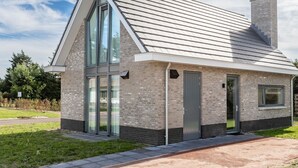 A modern house with a sloped roof, large glass windows, and a brick exterior. - Wonderful private villa for 6 people with WIFI, TV and terrace (Noordwijkerhout)