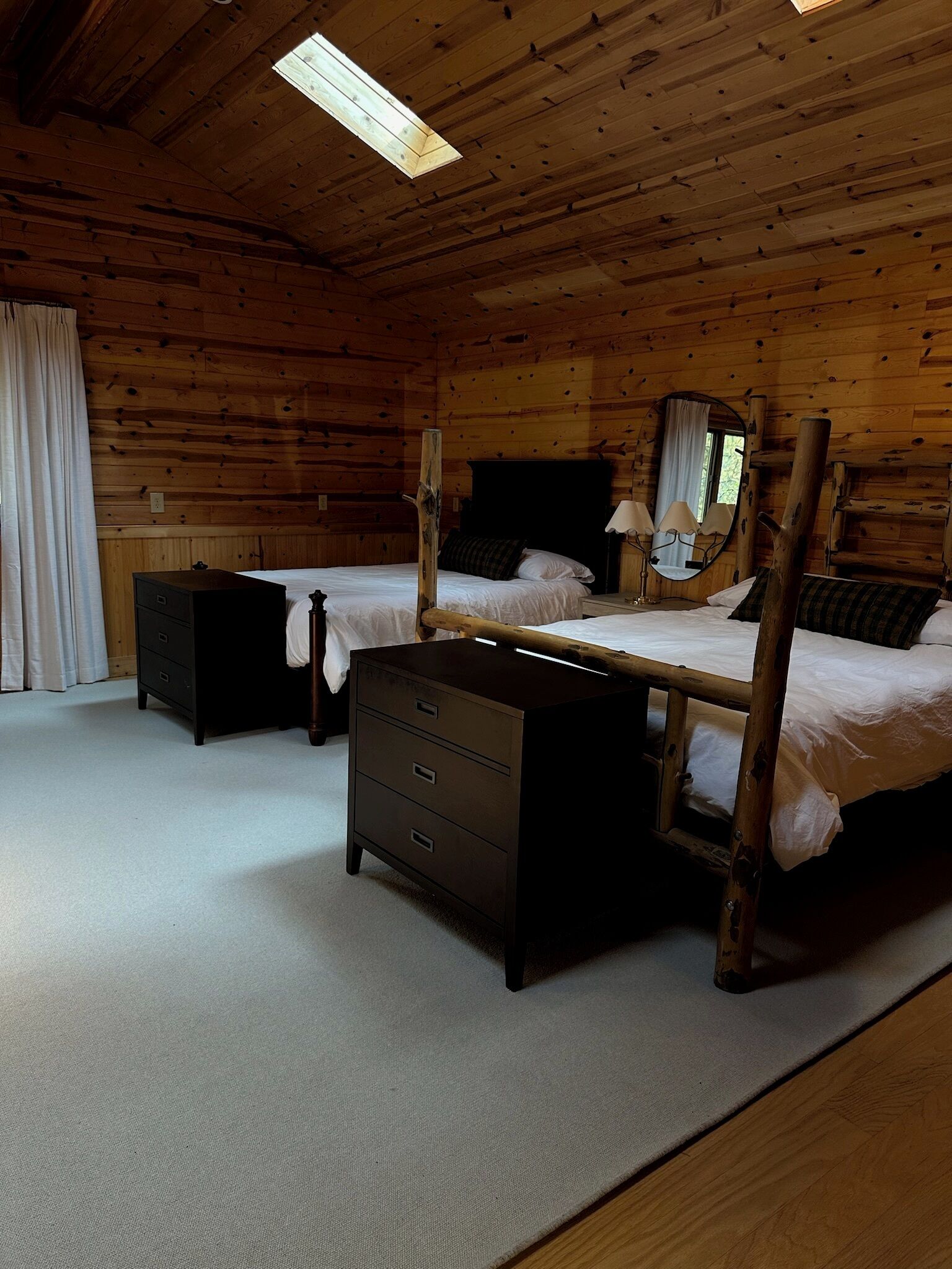 Een slaapkamer in een blokhut met twee bedden, een dressoir en een spiegel.