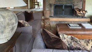 Un salón acogedor con chimenea de piedra, un sofá grande y una mesa de centro de madera.