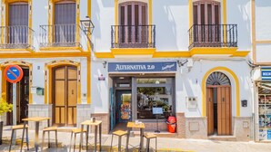 Un edificio con un restaurante llamado "Alternativa 2.0", con terraza y una calle adoquinada.