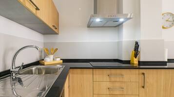 Een moderne keuken met een roestvrijstalen spoelbak, houten kastjes en een zwart aanrecht.