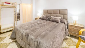 Un dormitorio moderno con una cama grande, una cama nido de madera, una mesita de noche con una lámpara y una silla.
