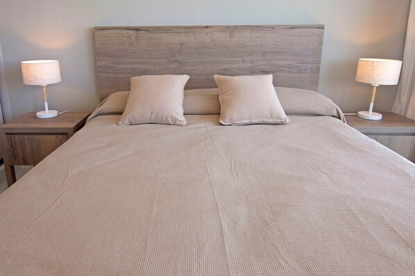 A bed with a wooden headboard, two bedside lamps, and two pillows. - Oceana Suites Cruceros III (Punta del Este)