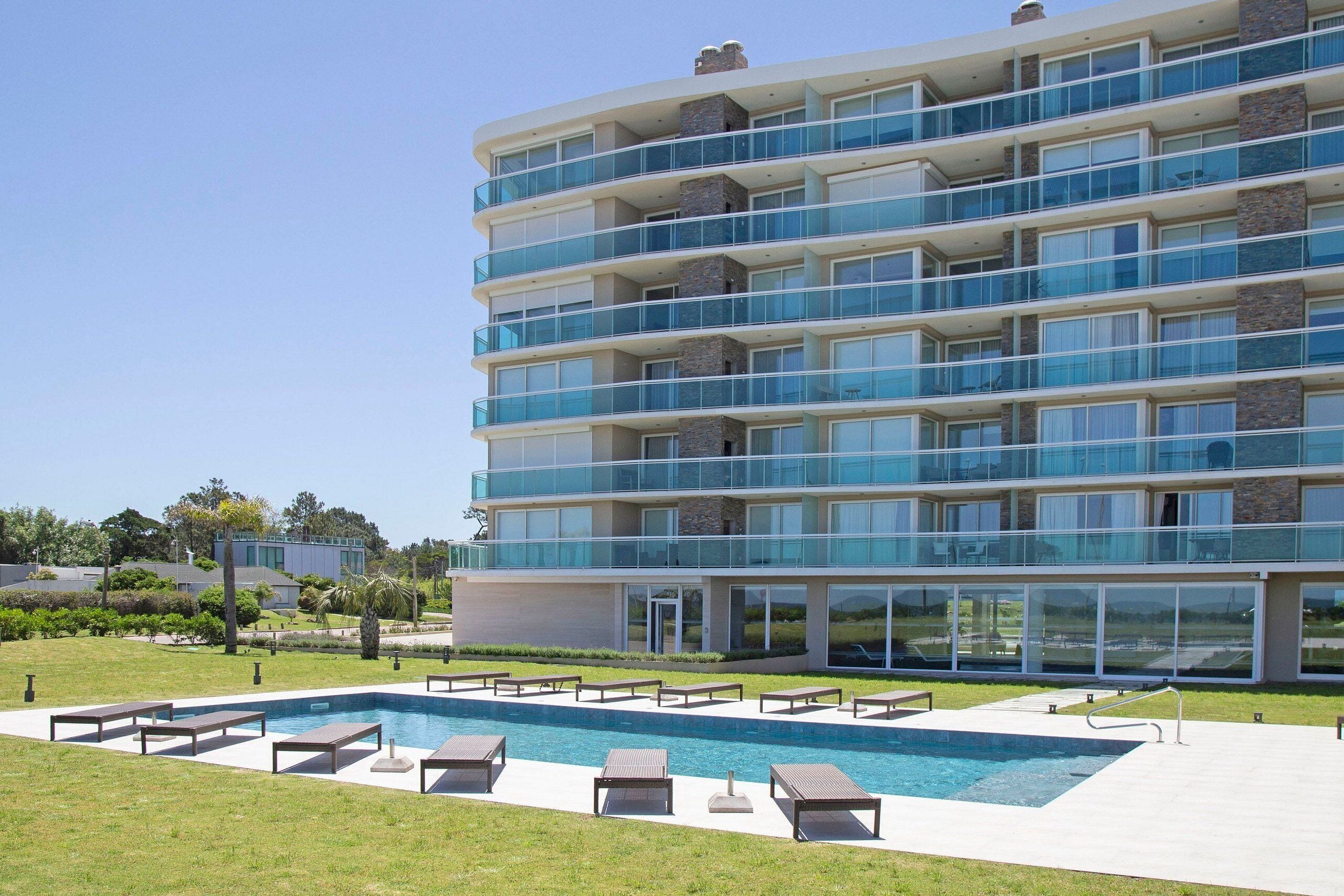A multi-story hotel with a pool area, outdoor seating, and a view of the surrounding landscape.