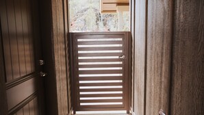 A wooden door with horizontal slats, leading to an outdoor area with a wooden structure and vegetation. - Cougar Canyon Unit C (Heber-Overgaard)