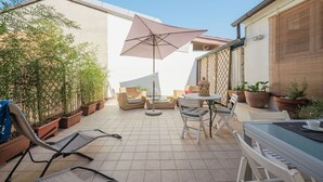 A patio area with a round table, chairs, and a large umbrella. There are potted plants and a bamboo fence. - Beautiful private villa for 8 people with A/C, TV and patio (Viareggio)