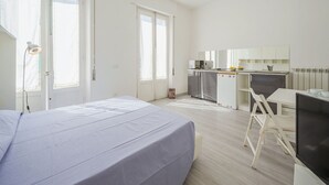 A modern, well-lit bedroom with a large bed, a desk, and a kitchenette. - Beautiful private villa for 8 people with A/C, TV and patio (Viareggio)