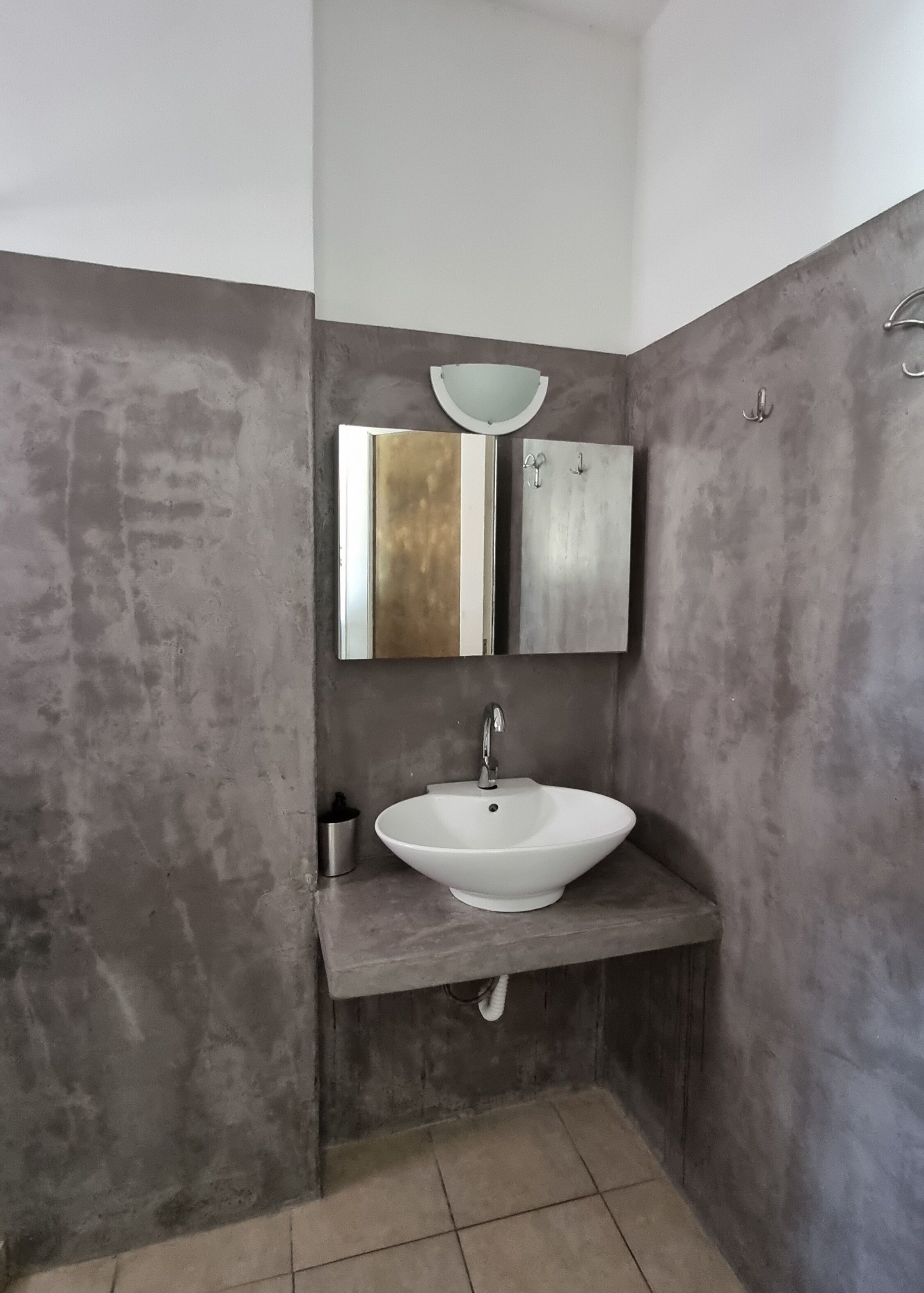 A bathroom with a white sink, a mirror, and a towel rack.