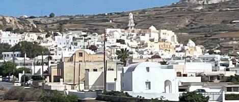 A coastal town with white buildings, a prominent church, and a hillside in the background.