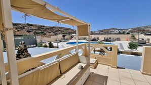 Zona de piscina en la azotea con sillones y vistas del paisaje circundante.
