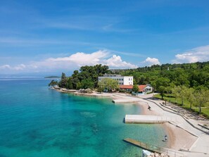 Eine Küstenlandschaft mit blauem Meer, einer Uferpromenade und Gebäuden im modernen Baustil.
