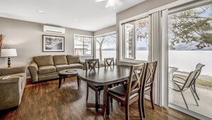 A spacious living room with a large dining table, a sofa, and a view of a lake.