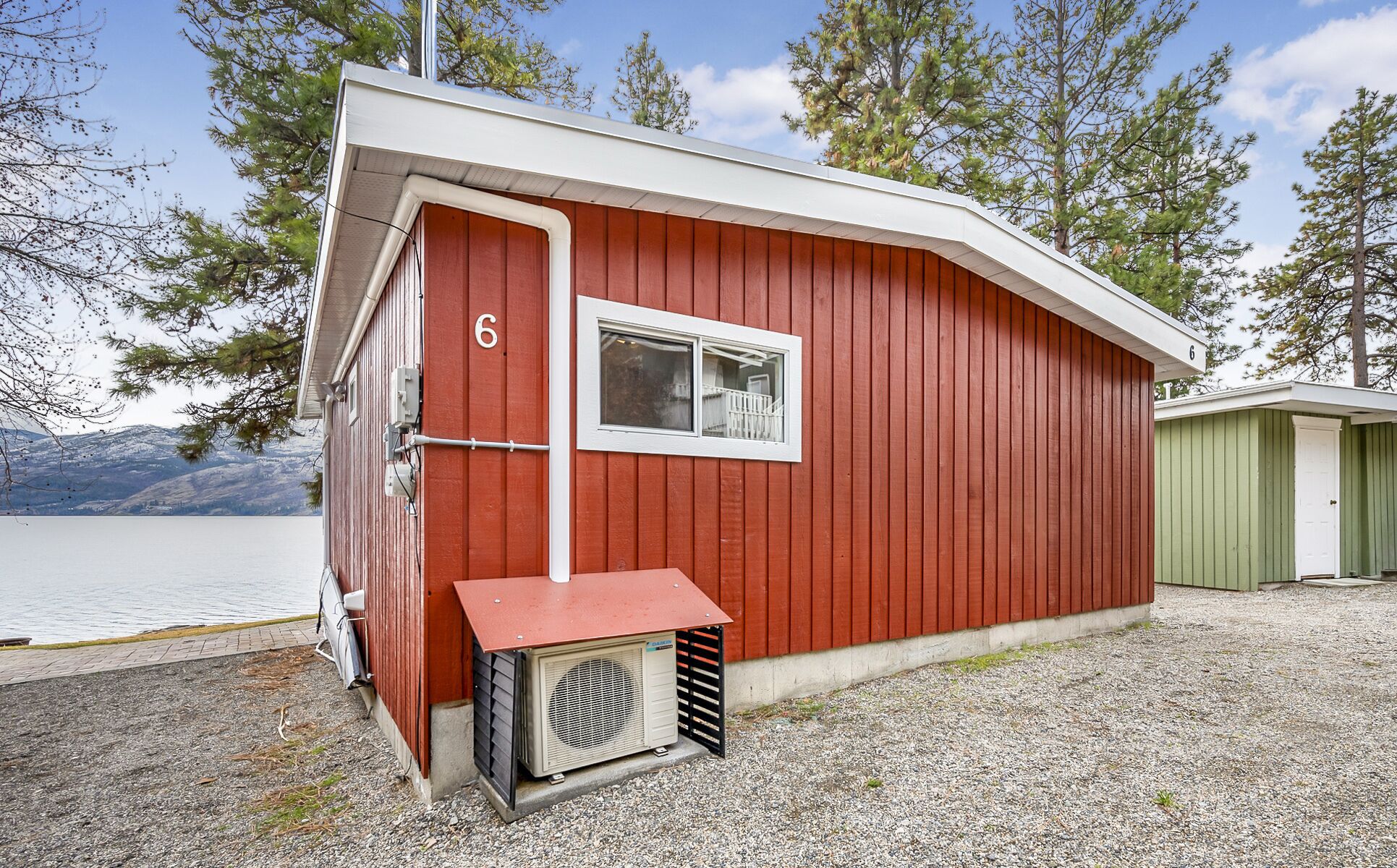 Eine rote Holzhütte mit Fenster und einer kleinen Klimaanlage davor.