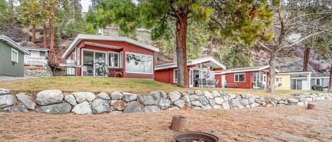 A red cabin with a stone wall and a fire pit in the foreground.