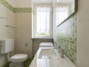 Ein Badezimmer mit Toilette, Waschbecken und einem Fenster mit Vorhängen.