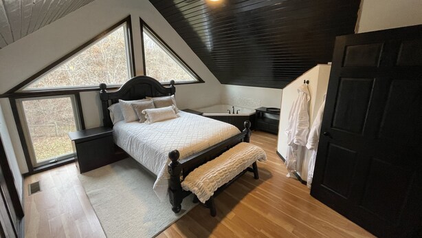 Une chambre à coucher avec un lit, un banc, une fenêtre, une baignoire et une porte.
