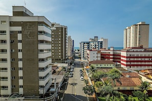 A cityscape with high-rise buildings, a clear sky, and a street lined with parked cars.