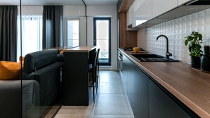 A modern kitchen with a wooden countertop, black cabinets, and a black faucet. - Sandra (Bucharest)