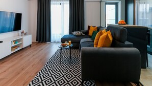A modern living room with a sofa, a coffee table, and a TV. - Sandra (Bucharest)