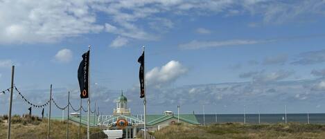 A pathway leading to a building with a green roof and a tower, surrounded by flags and a fence.