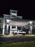 A hotel with a covered parking area, a white pickup truck parked in front, and a sign reading "spark by Hilton".