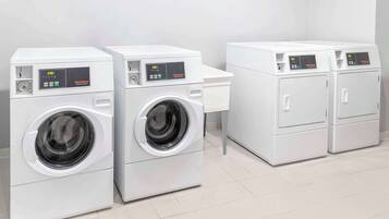 A row of white front-loading washing machines in a clean, tiled room.