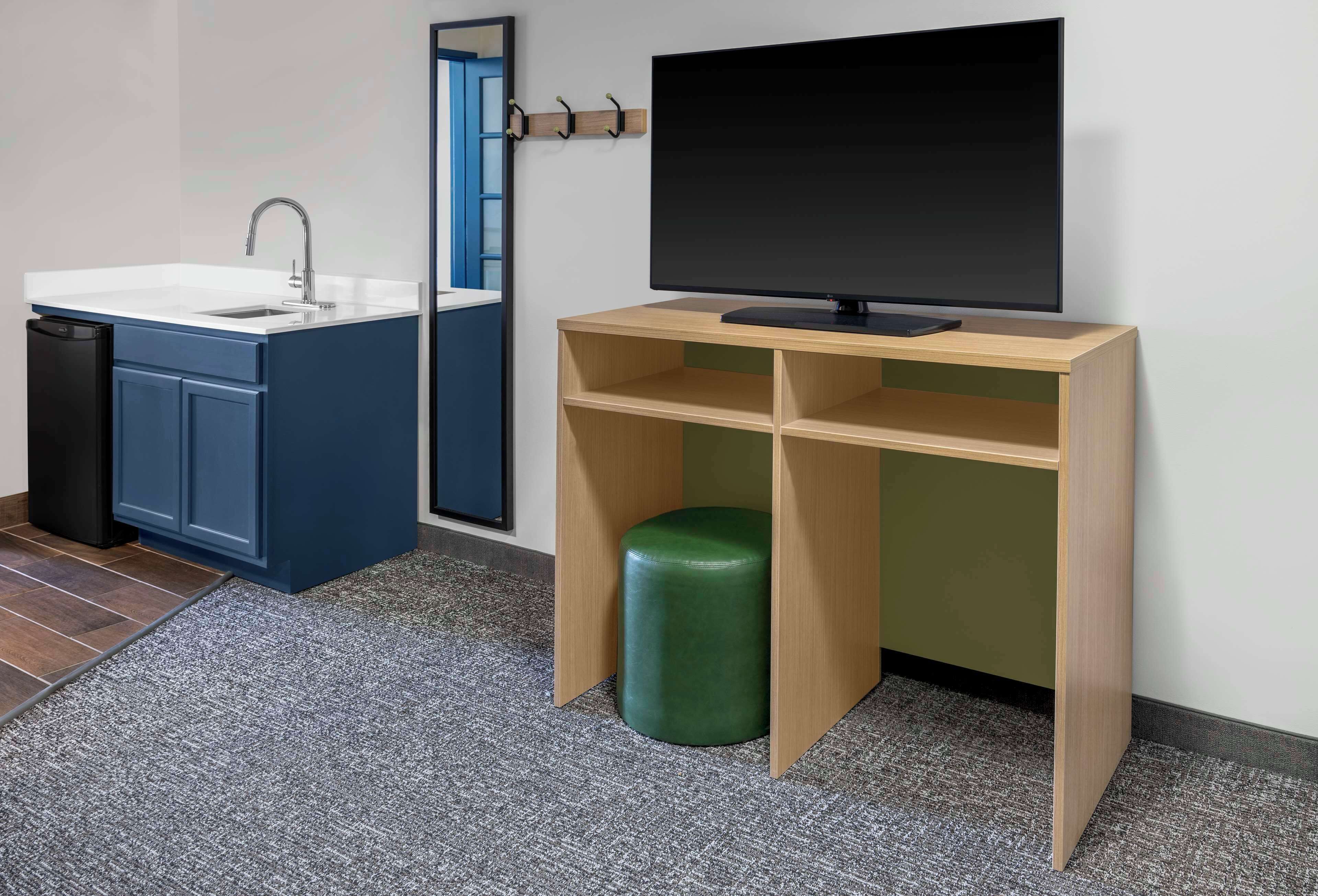 A modern bathroom with a sink, mirror, and a television on a wooden stand.