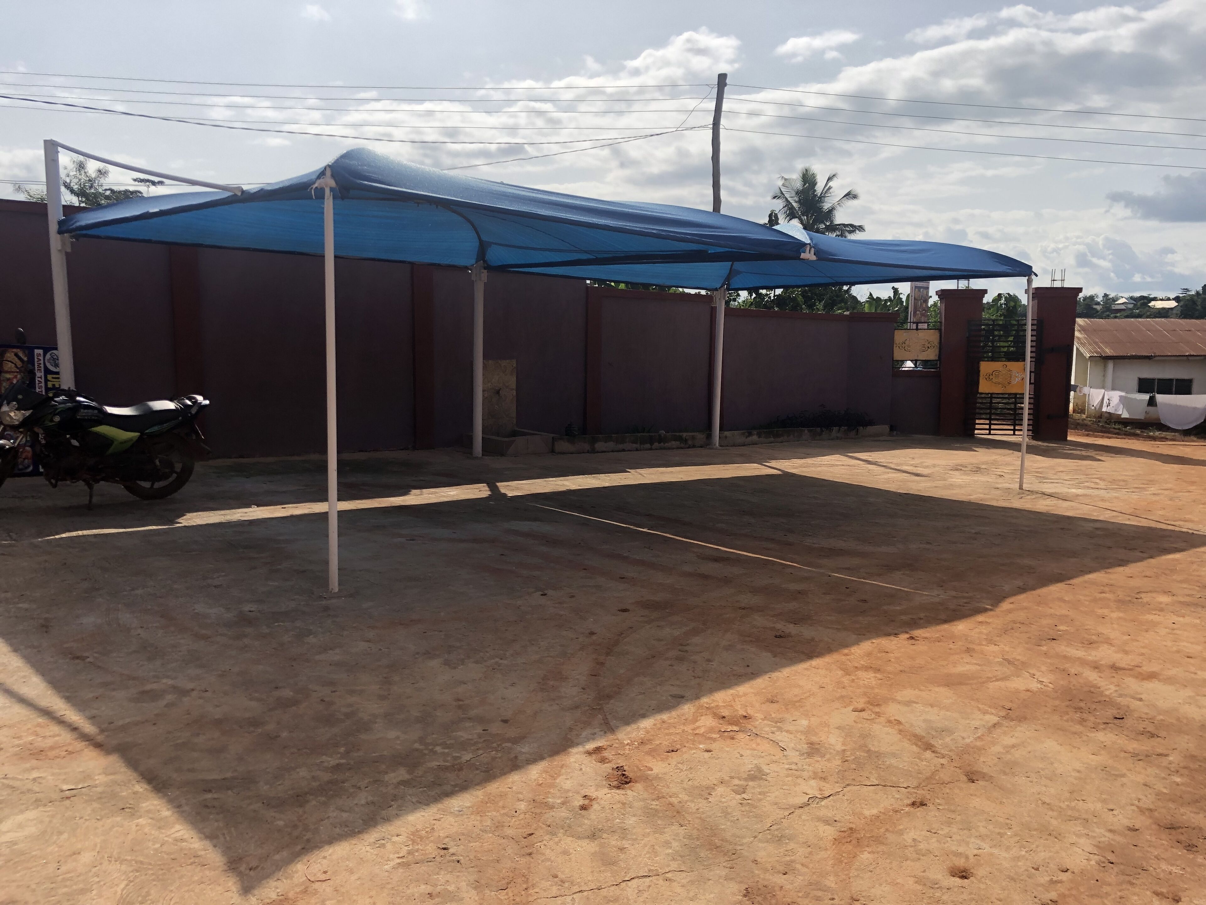 A covered outdoor area with a motorcycle parked under a blue canopy.