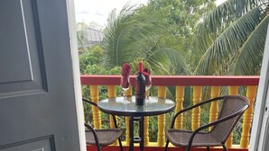 A balcony with a table and chairs, a glass door, and a view of greenery.