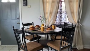 A dining area with a round table, four chairs, and a vase with flowers.