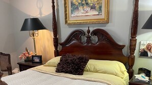 A bedroom with a four-poster bed, a large painting above the bed, a lamp on the nightstand, and a framed photo on the wall. - Great Masters rental, walking distance to the tournament. (Augusta)
