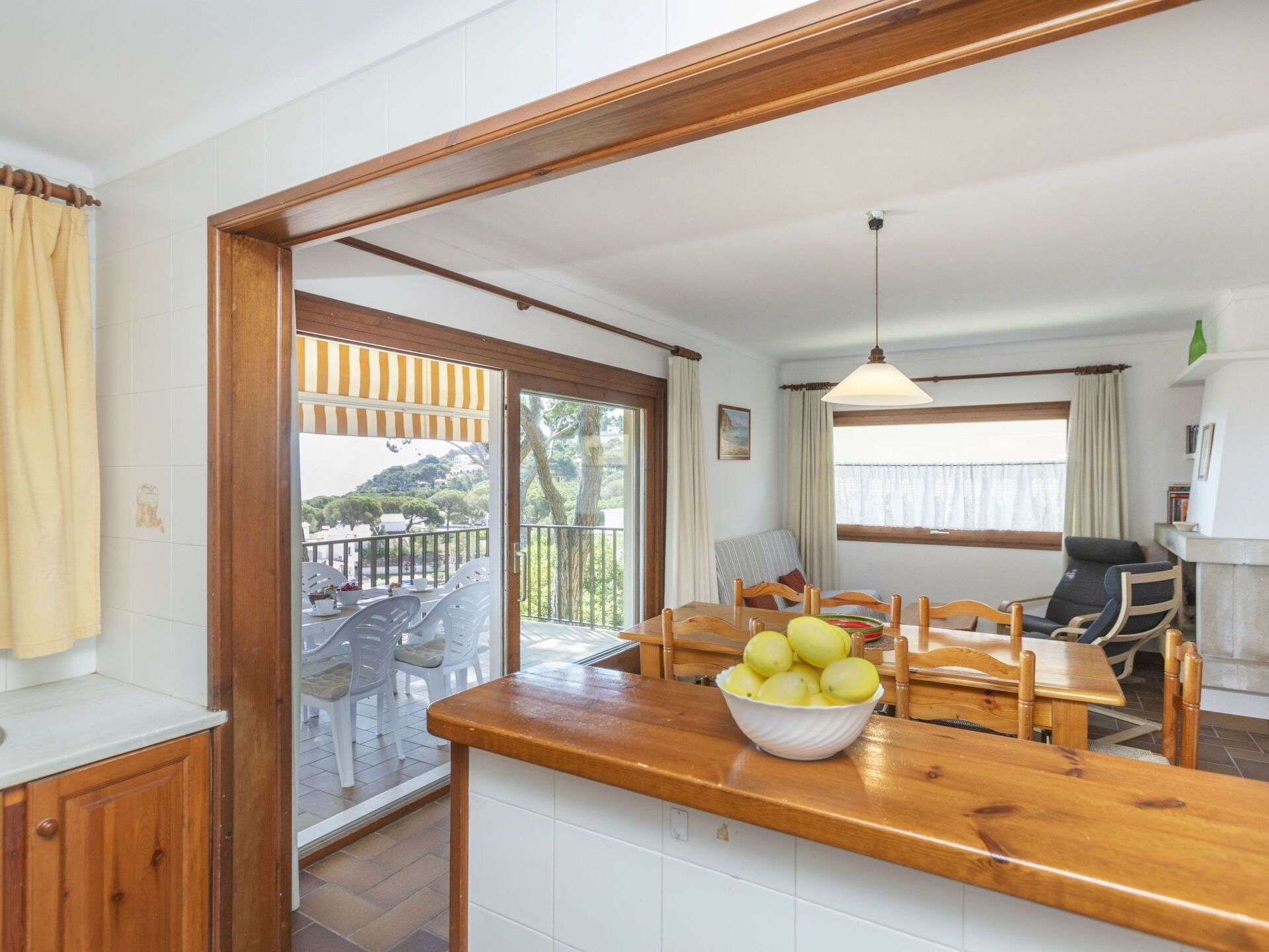 A kitchen with a wooden countertop, a bowl of lemons, and a dining area with chairs and a table.