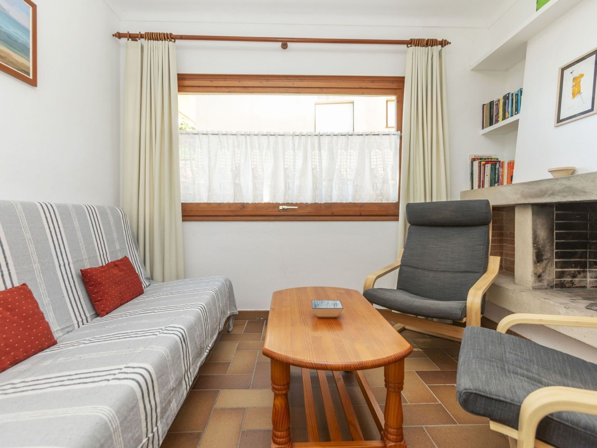 A cozy living room with a sofa, armchair, and a small wooden table. A fireplace is visible in the background.